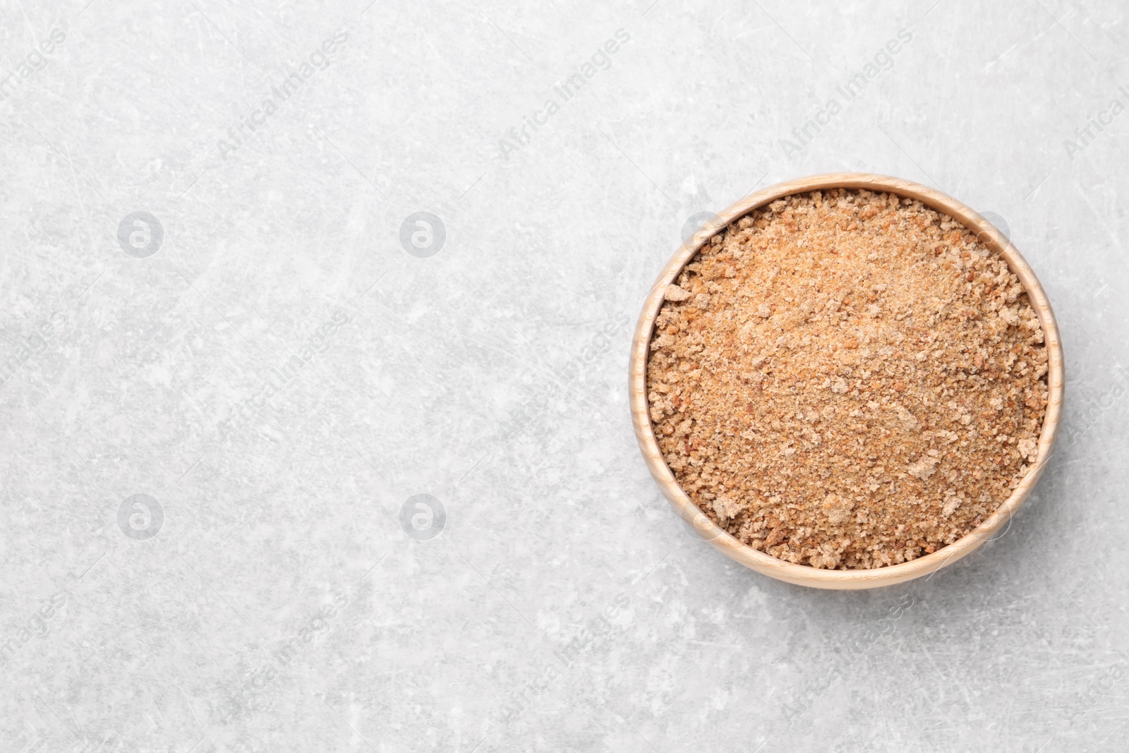 Photo of Fresh bread crumbs in bowl on grey table, top view. Space for text