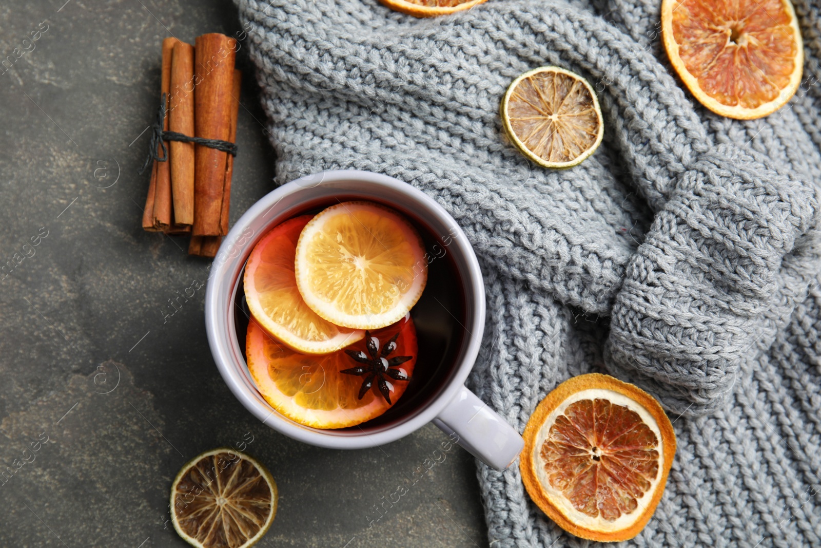 Photo of Flat lay composition with cup of hot winter drink and warm knitted sweater on gray background. Cozy season