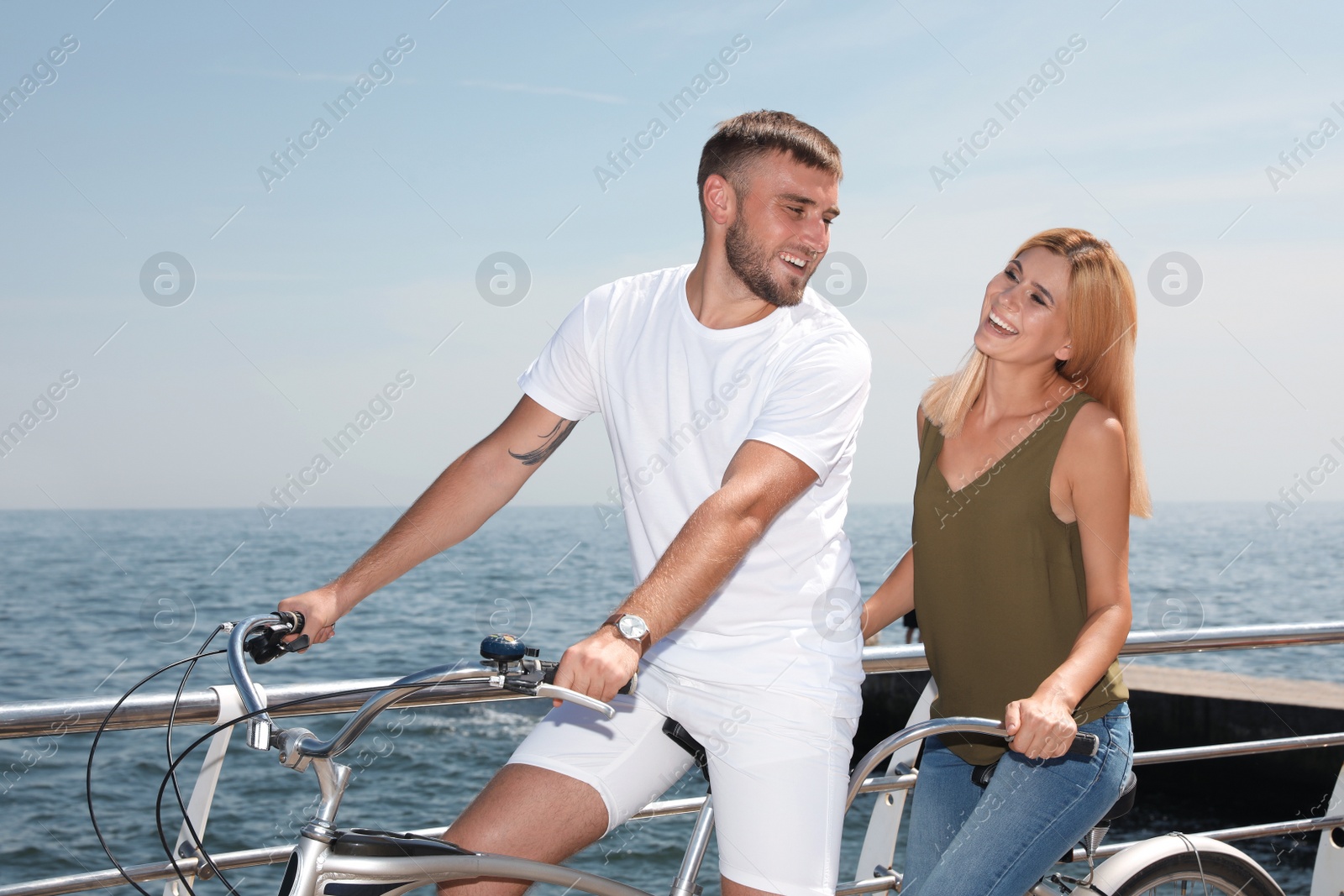 Photo of Couple riding tandem bike near sea on sunny day