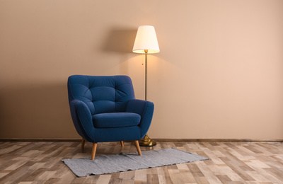 Photo of Comfortable armchair with floor lamp and rug indoors