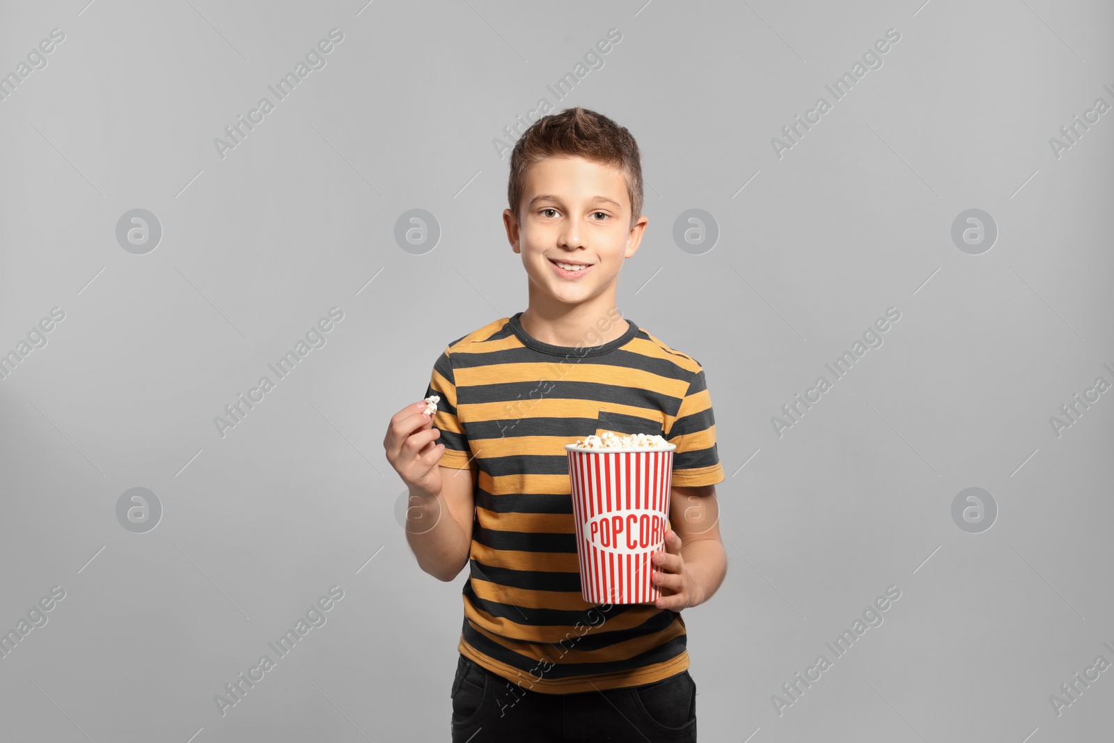 Photo of Boy with popcorn during cinema show on grey background