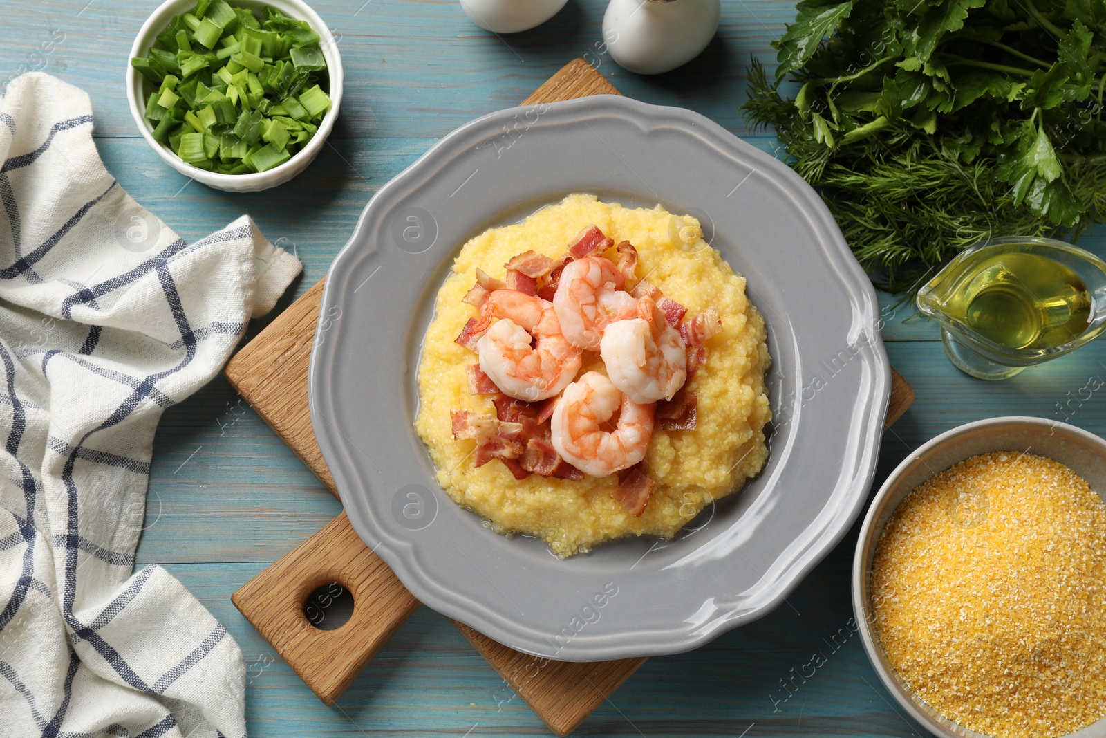 Photo of Plate with fresh tasty shrimps, bacon, grits and green onion on light blue wooden table, flat lay