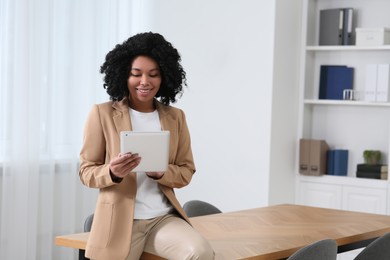 Photo of Smiling young businesswoman using tablet in modern office