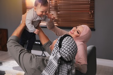 Happy Muslim family with little son in living room