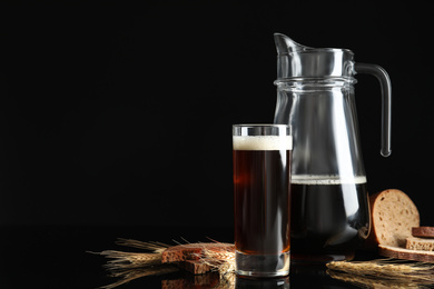 Delicious kvass, bread and spikes on black background. Space for text