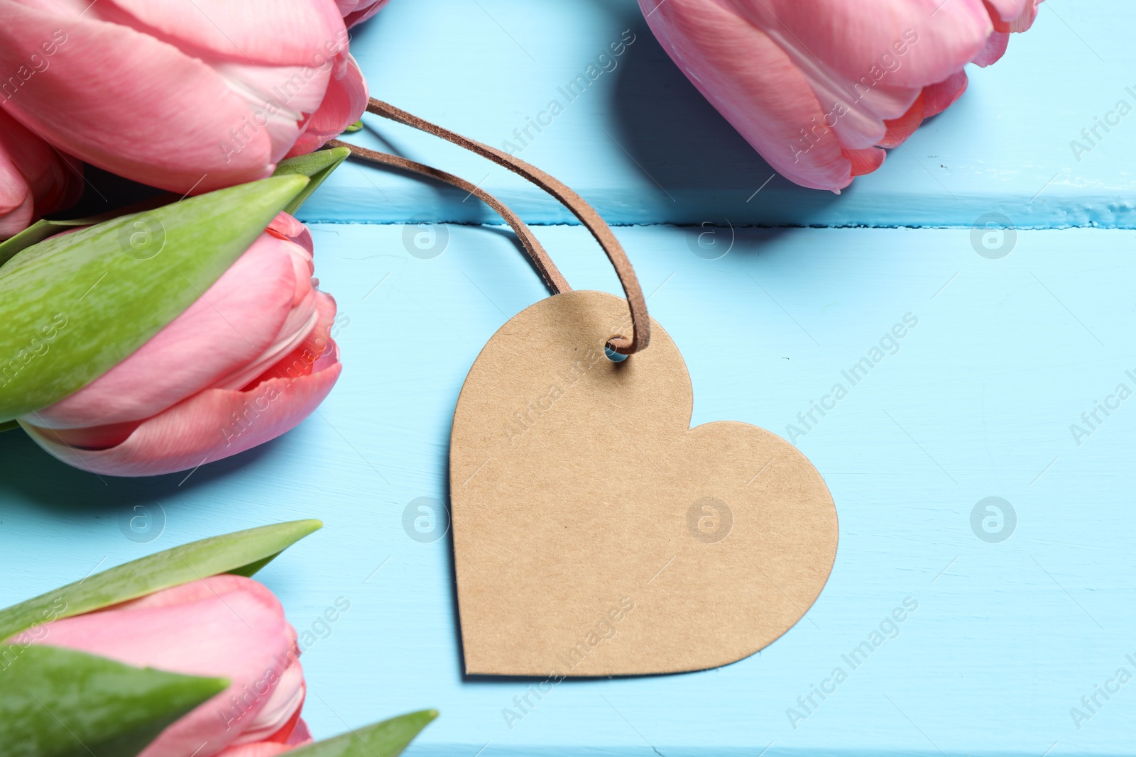 Photo of Happy Mother's Day. Beautiful pink tulips and blank heart shaped card on light blue wooden table, flat lay