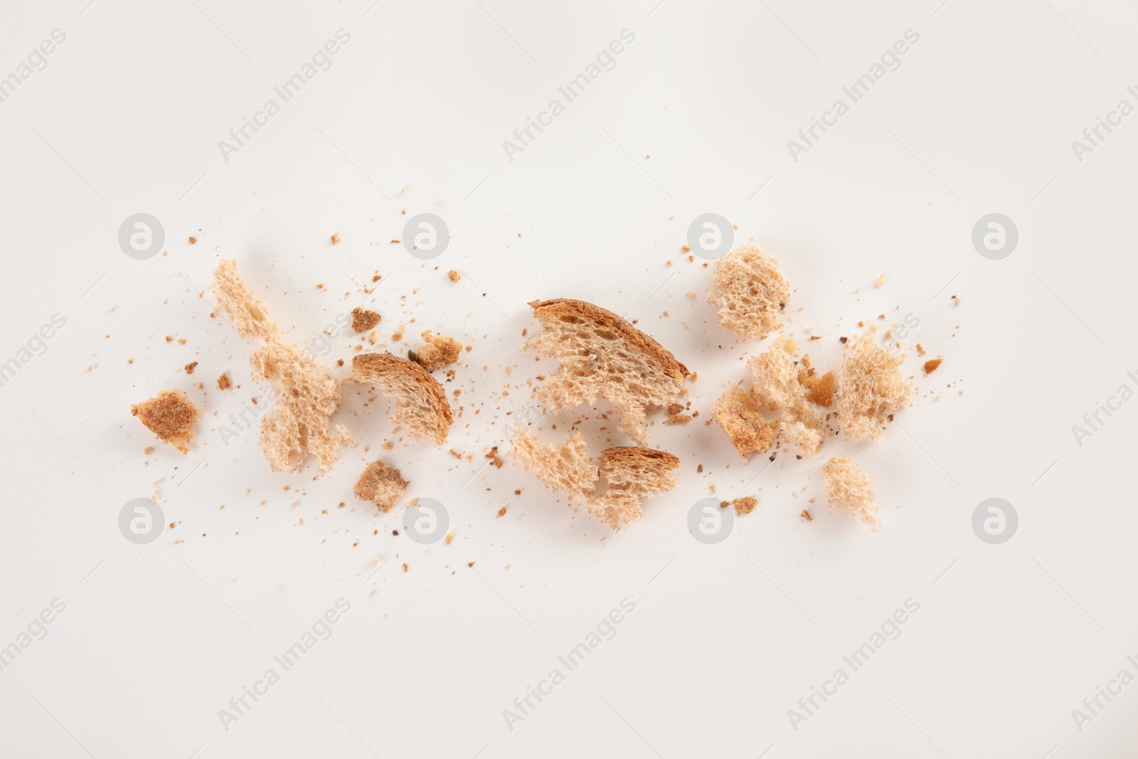 Photo of Scattered bread crumbs on white background, top view