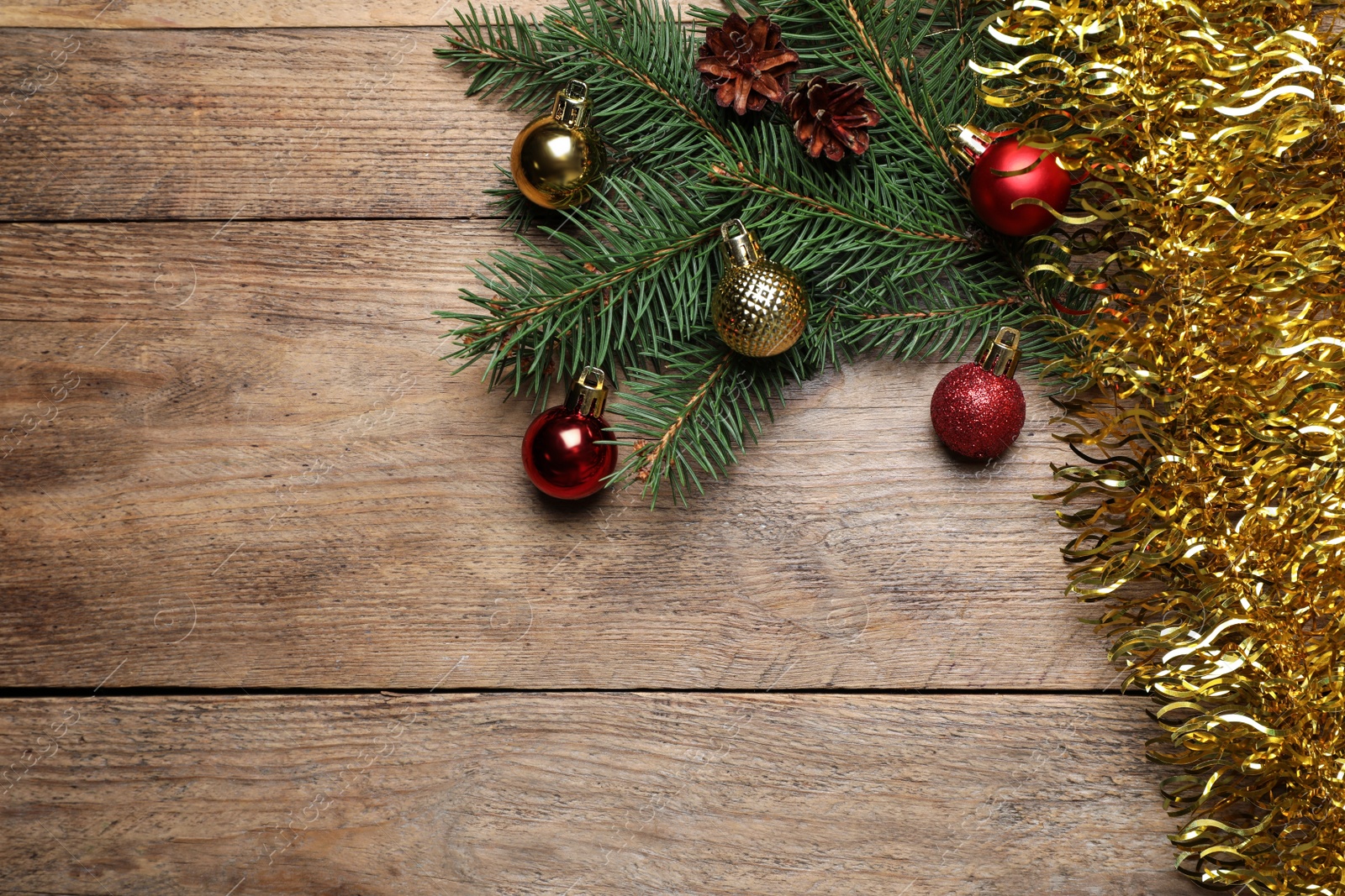 Photo of Bright tinsel, fir tree branches and Christmas balls on wooden background, flat lay. Space for text