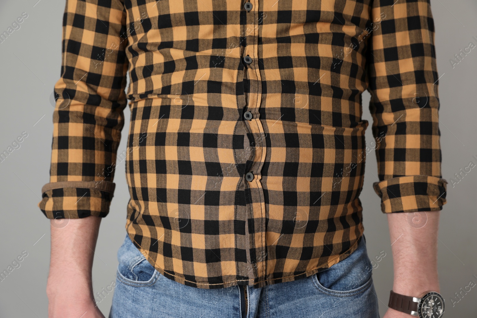 Photo of Overweight man in tight shirt on grey background, closeup