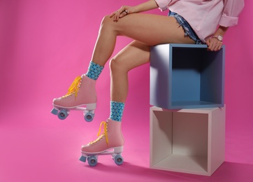 Photo of Young woman with retro roller skates on color background, closeup