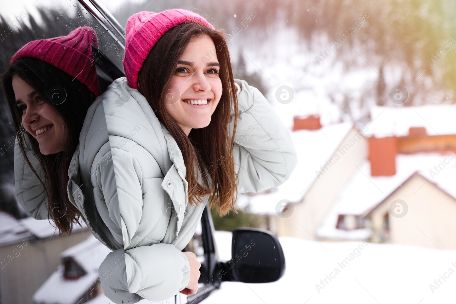 Photo of Happy young woman looking out of car window on road. Winter vacation