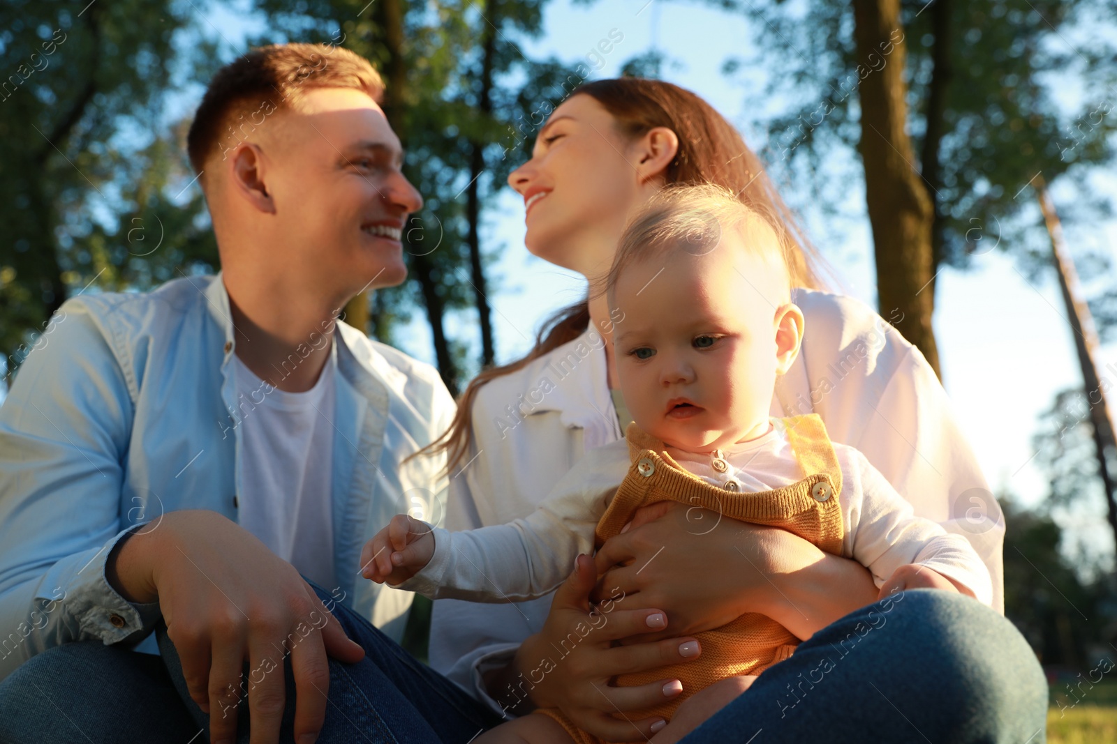 Photo of Parents with their cute daughter spending time together in park on summer day