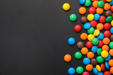 Photo of Colorful candies on black background, top view. Space for text