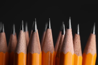Photo of Many graphite pencils on black background, macro view