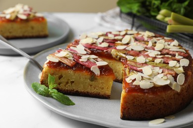 Photo of Freshly baked rhubarb pie with almond flakes and cake server on white table, closeup