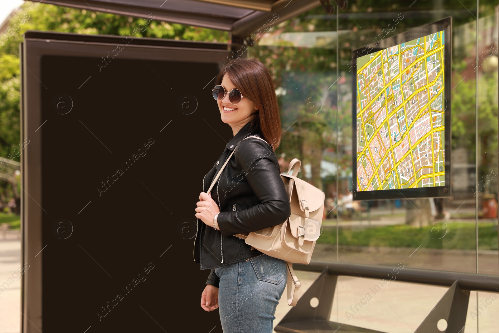 Image of Young woman waiting for public transport at bus stop