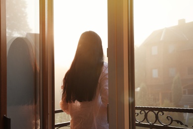 Young woman standing on balcony in early morning