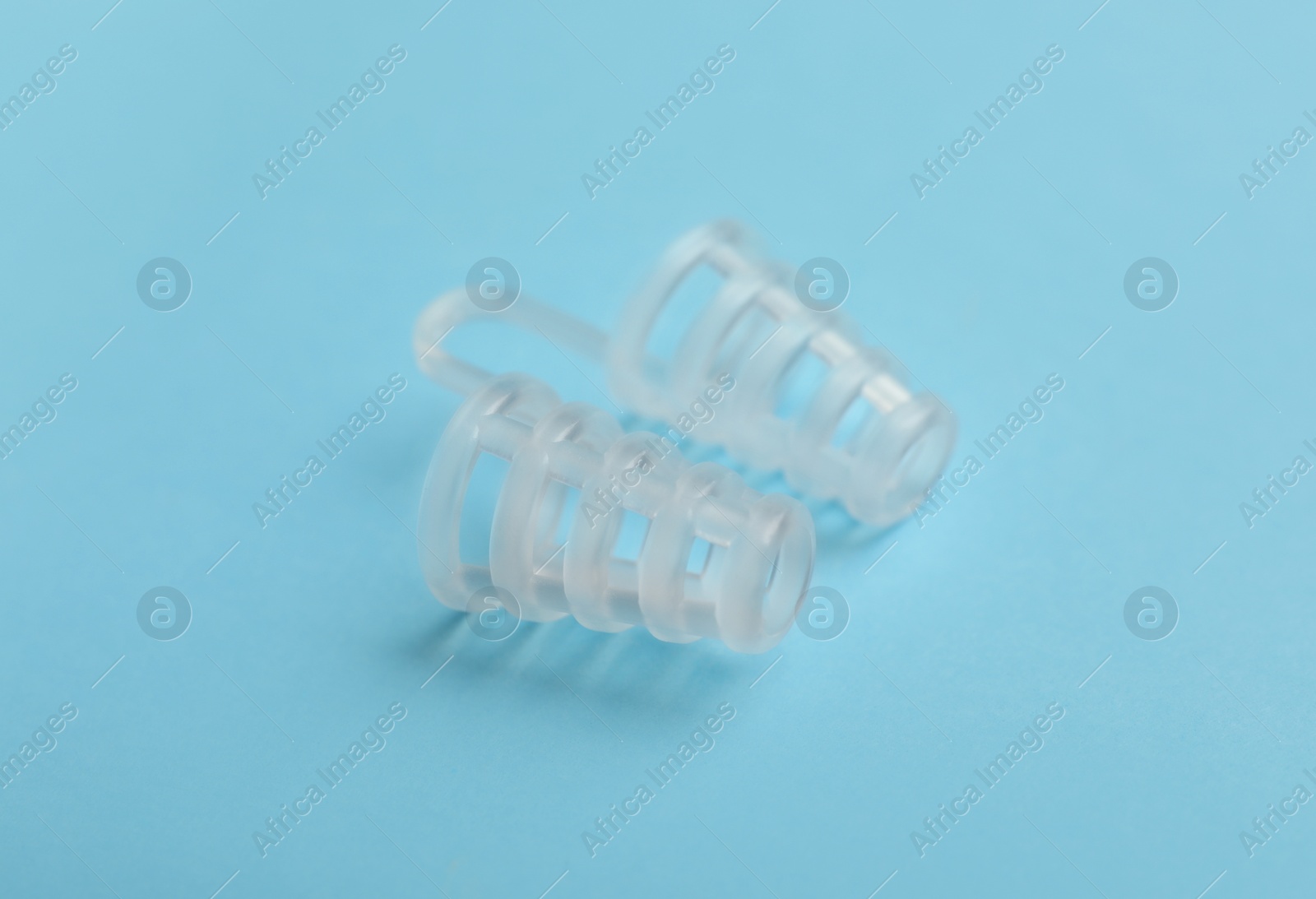 Photo of Anti-snoring device for nose on light blue background, closeup