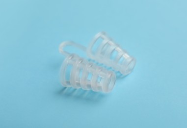 Photo of Anti-snoring device for nose on light blue background, closeup