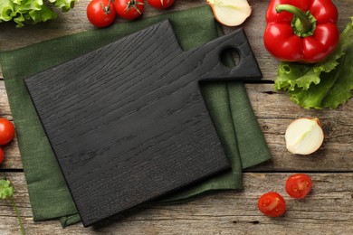 Flat lay composition with black cutting board and products on wooden table
