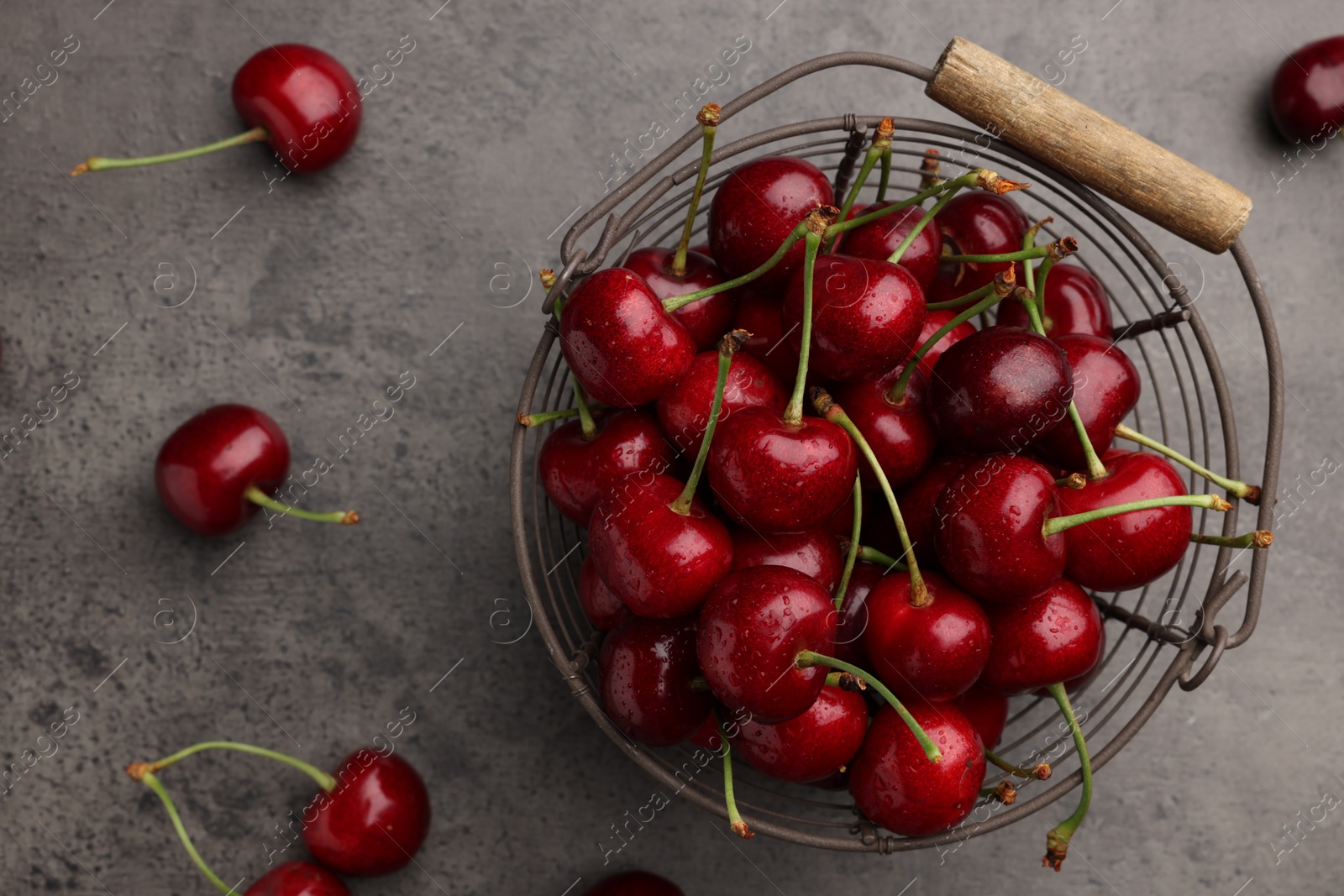 Photo of Metal basket with ripe sweet cherries on grey table, flat lay
