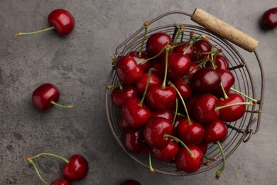 Photo of Metal basket with ripe sweet cherries on grey table, flat lay