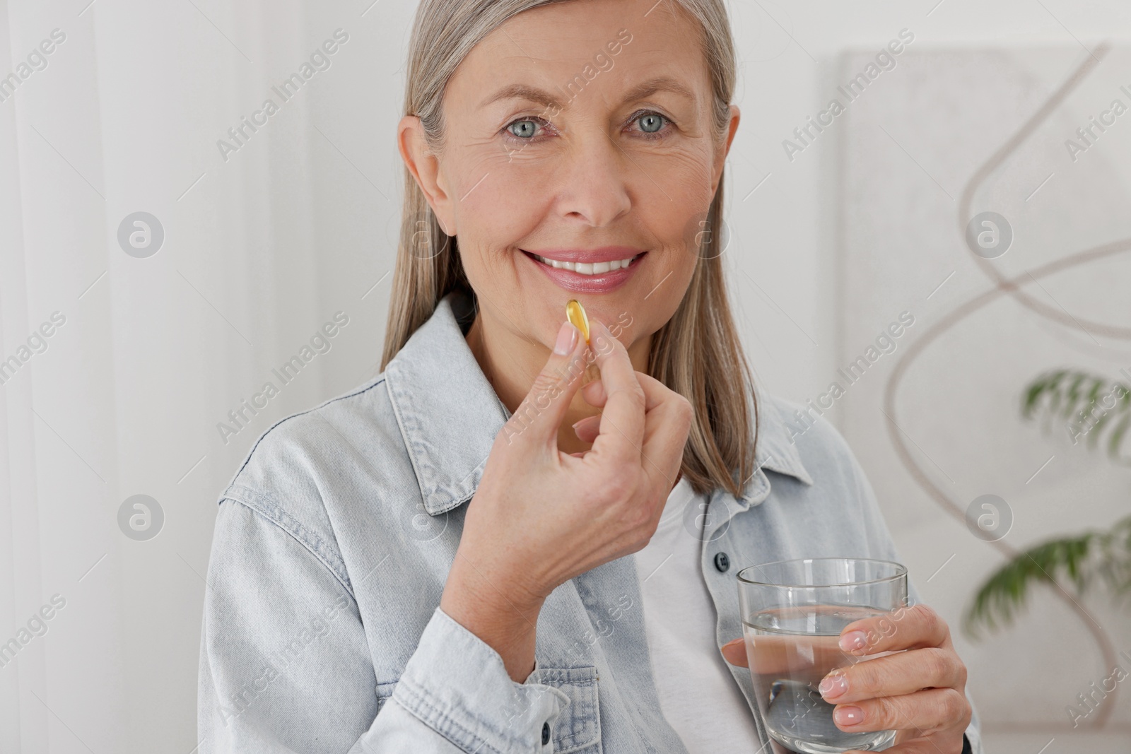 Photo of Beautiful woman taking vitamin pill at home