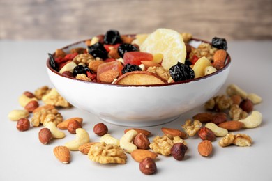 Bowl with mixed dried fruits and nuts on white background, closeup