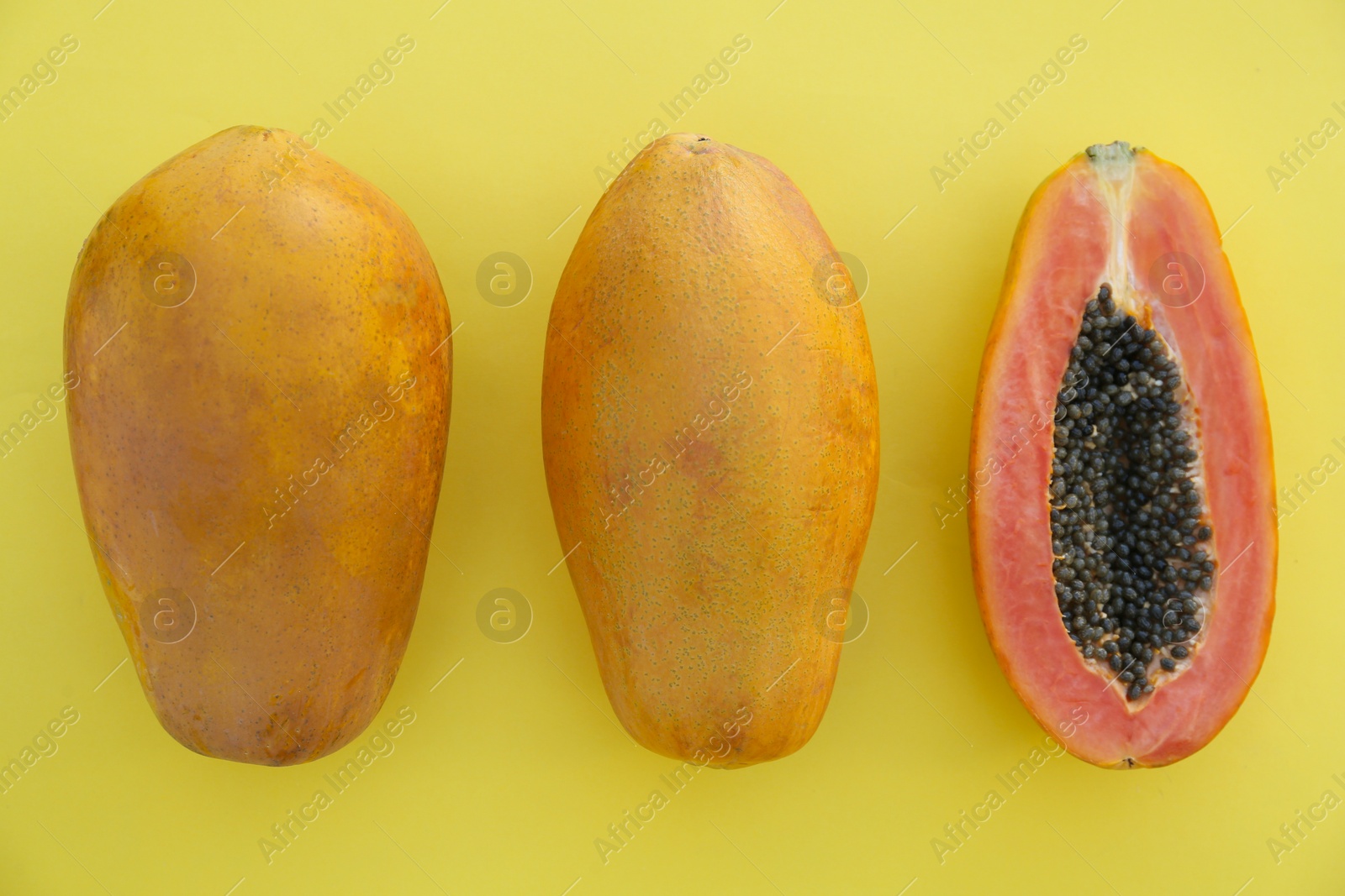 Photo of Fresh ripe cut and whole papaya fruits on light green background, flat lay