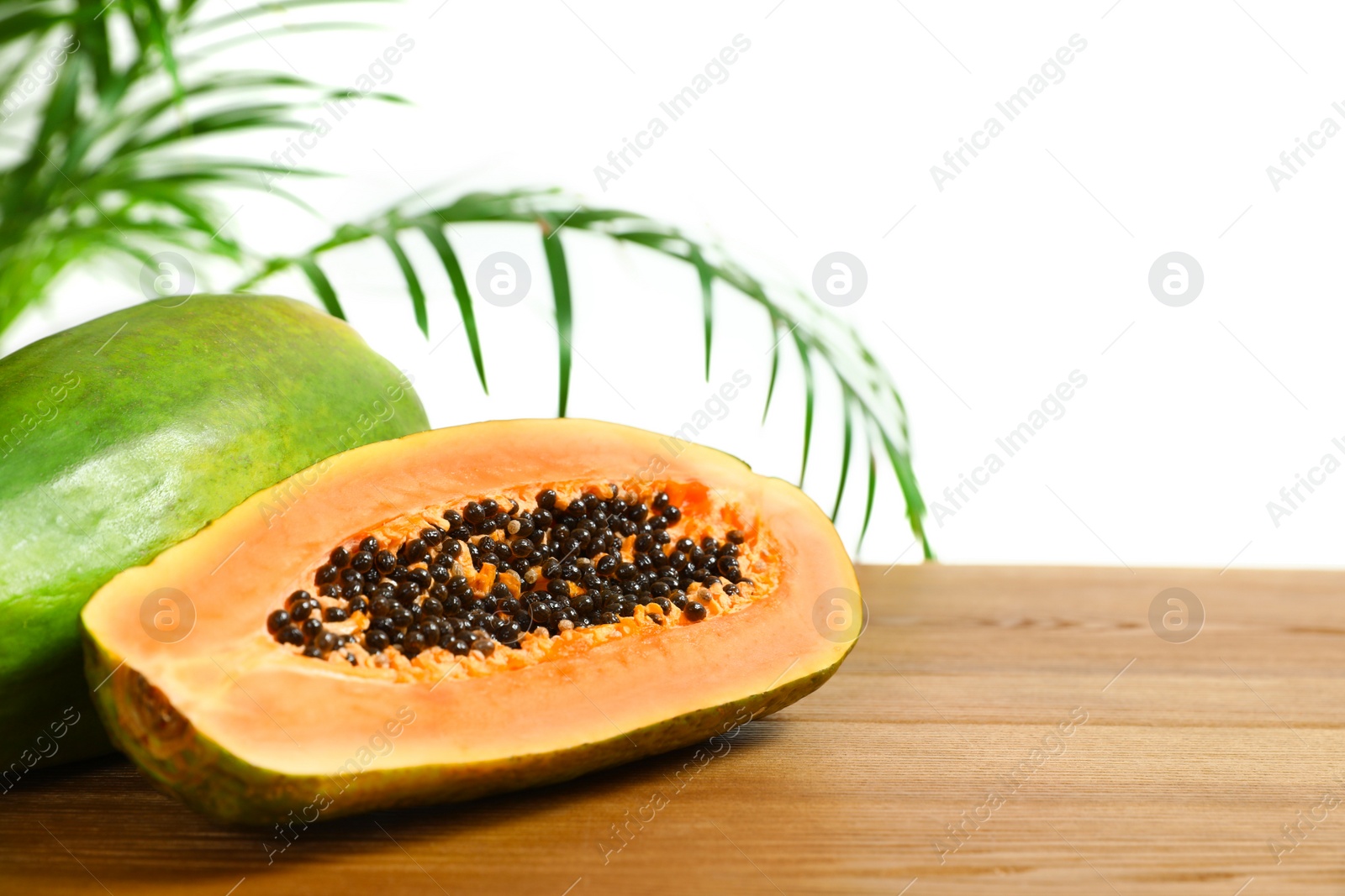 Photo of Fresh juicy papayas on wooden table against blurred background, space for text