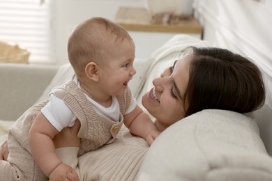 Photo of Happy young mother with her baby on sofa in living room