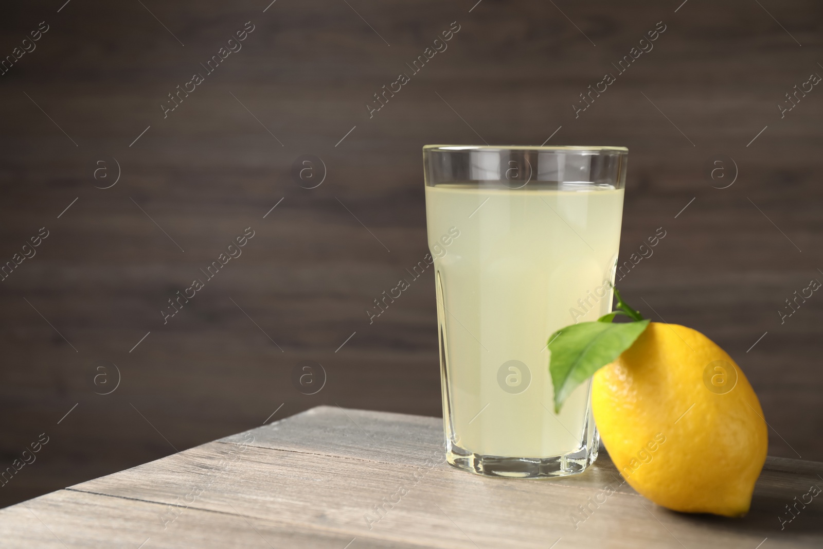 Photo of Delicious refreshing lemonade and fruit on wooden table, space for text