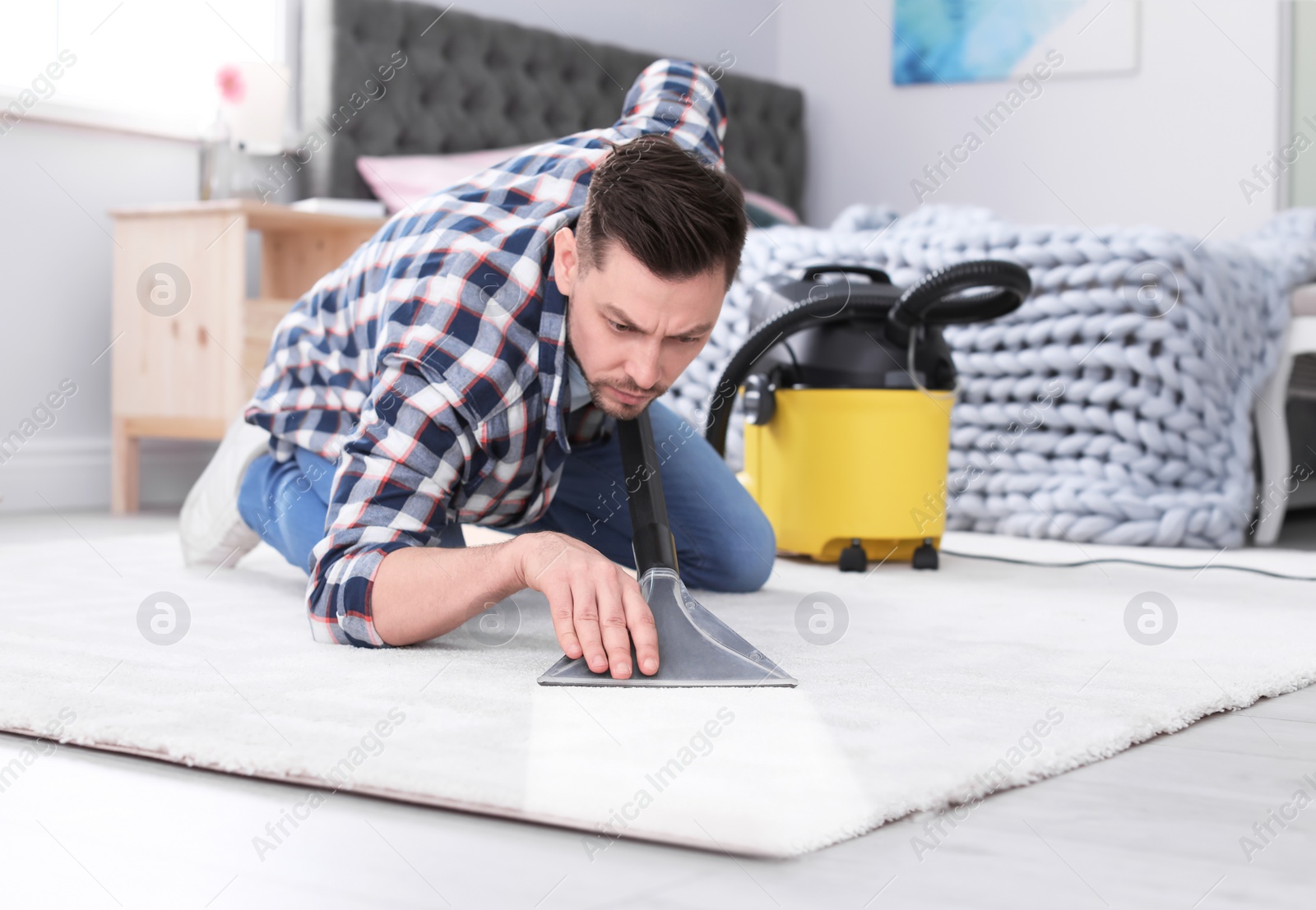 Photo of Mature man hoovering carpet with vacuum cleaner at home