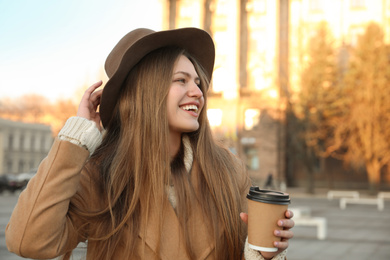 Photo of Young woman with cup of coffee on city street in morning