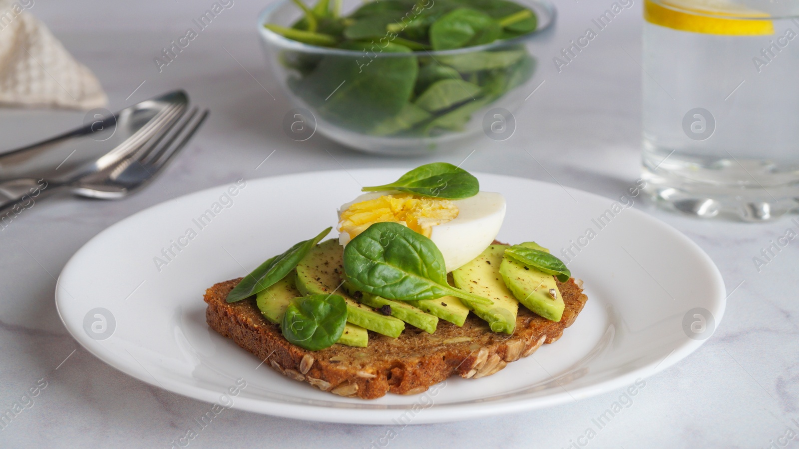 Photo of Tasty sandwich with boiled egg and avocado on white marble table