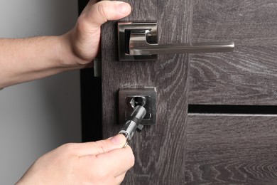 Handyman changing core of door lock indoors, closeup