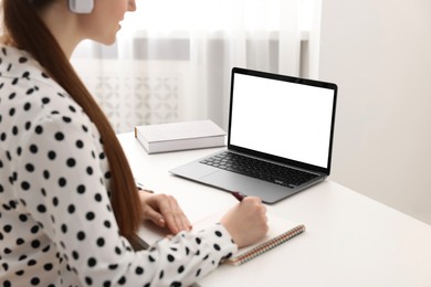 E-learning. Woman taking notes during online lesson at table indoors, closeup