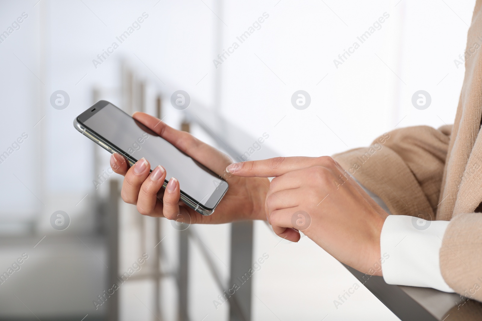 Photo of Young woman using modern smartphone indoors, closeup