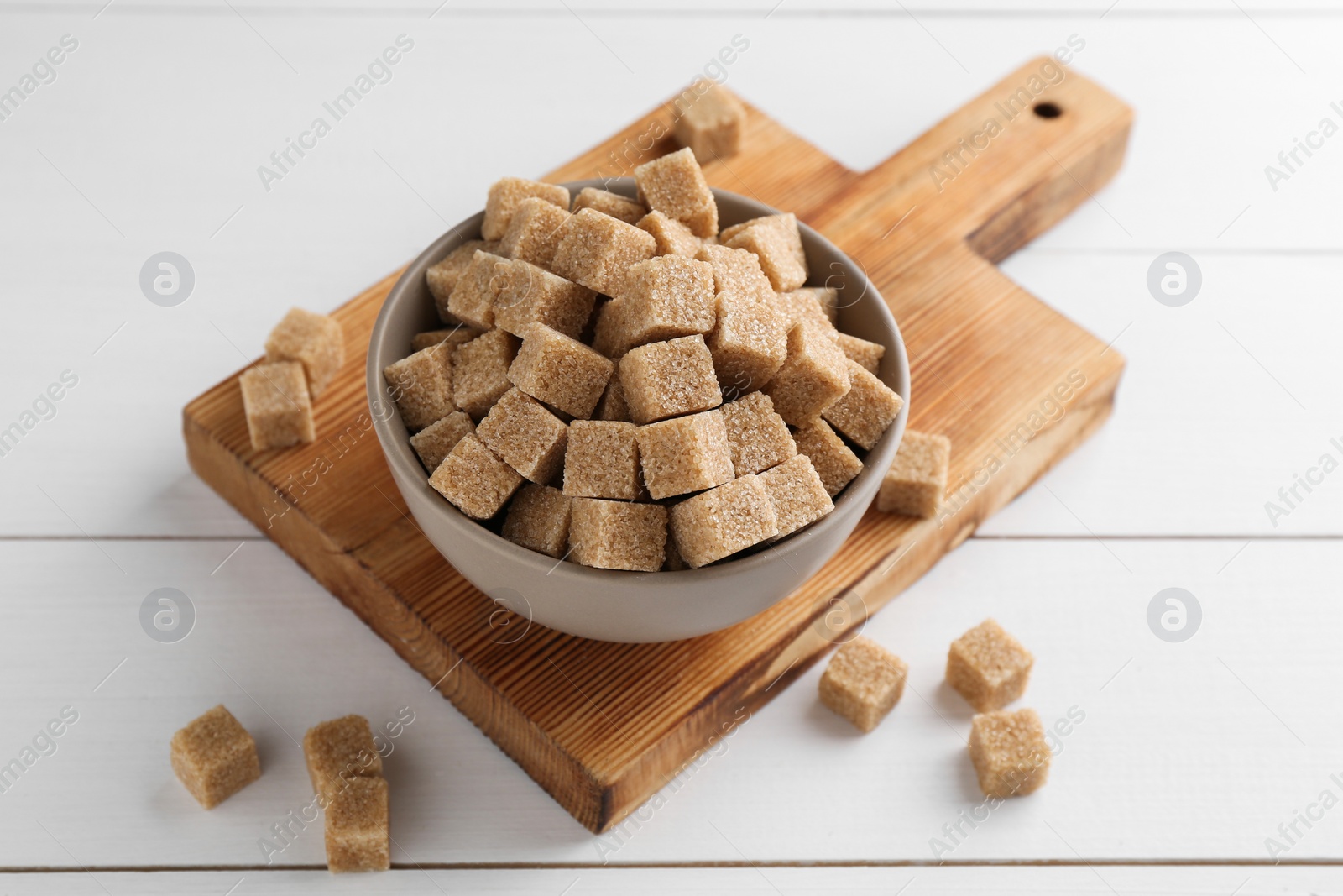 Photo of Brown sugar cubes on white wooden table