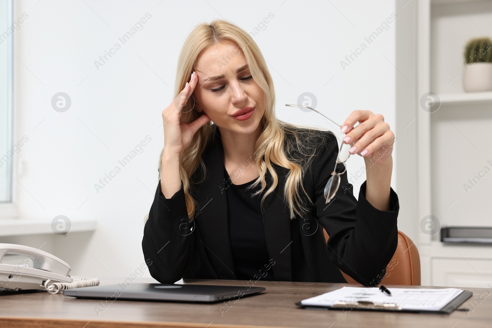 Photo of Overwhelmed woman with glasses at wooden table in office