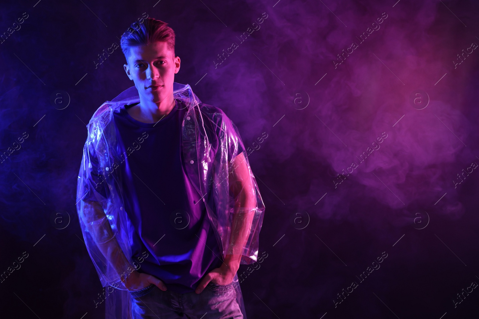 Photo of Young man wearing clear coat in neon lights with smoke effect. Space for text