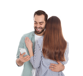 Photo of Man interested in smartphone while hugging his girlfriend on white background. Relationship problems