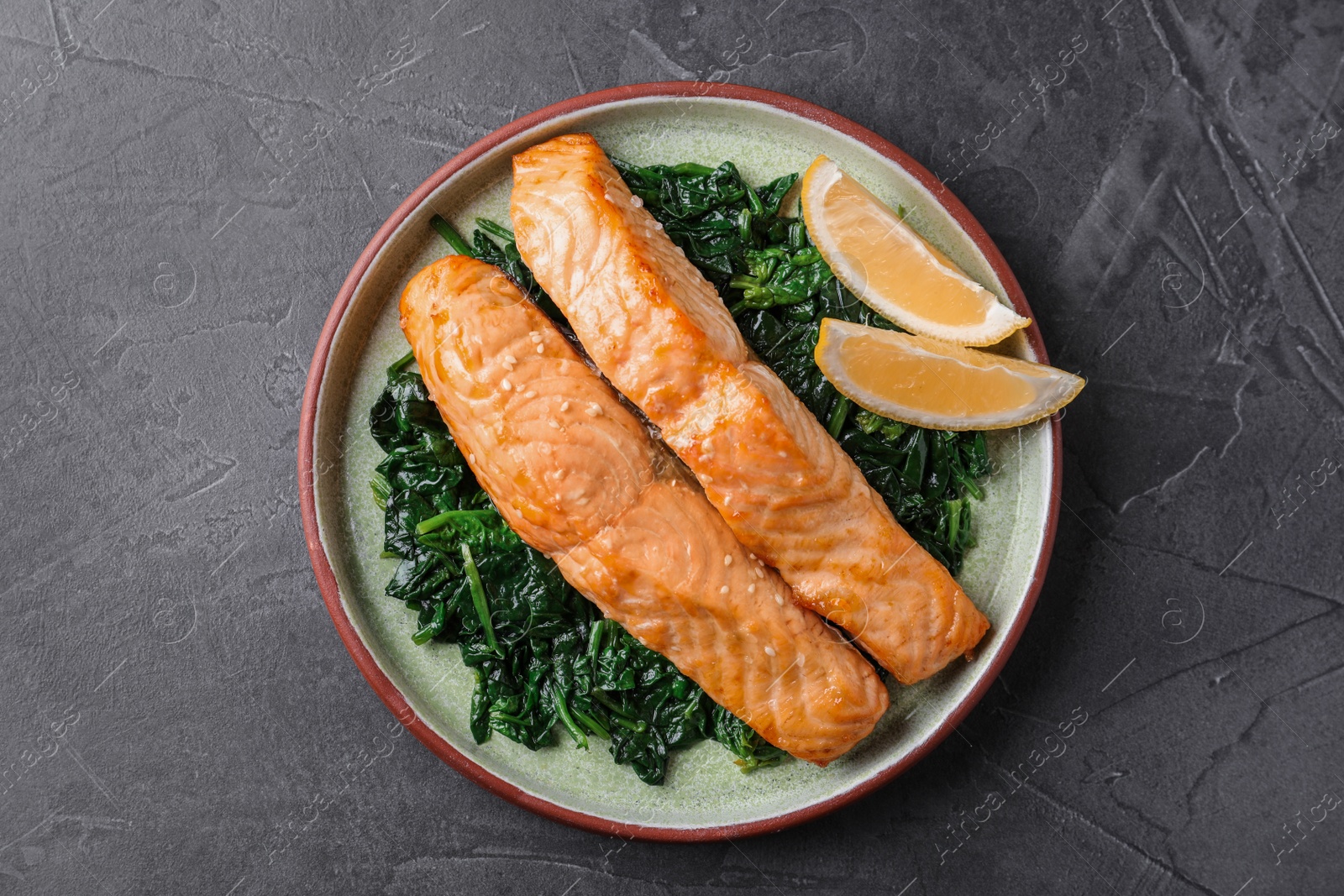 Photo of Tasty salmon with spinach and lemon on grey table, top view