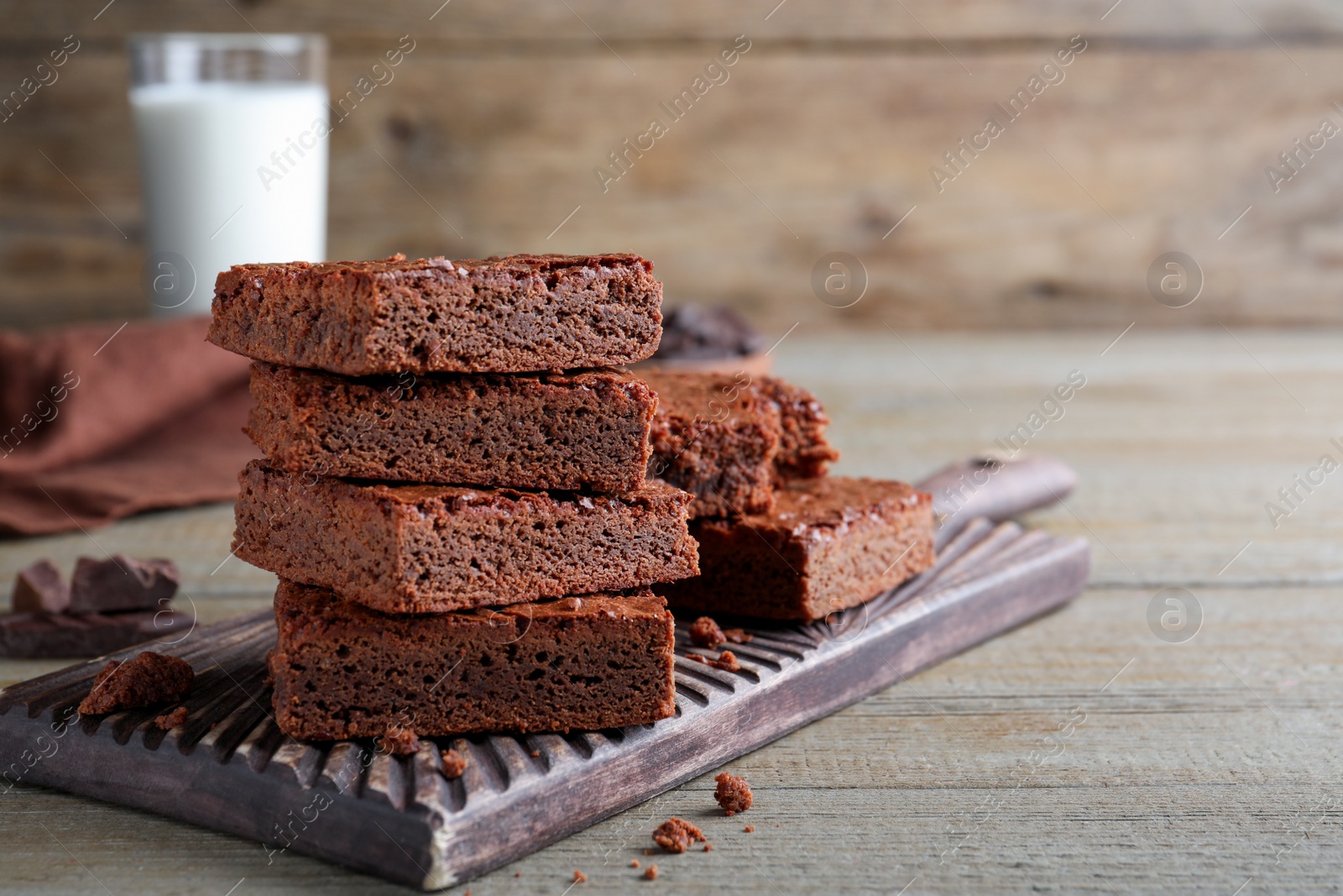 Photo of Delicious chocolate brownies on wooden table. Space for text