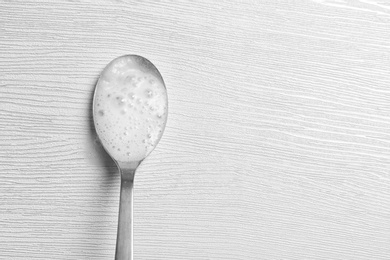 Photo of Chemical reaction of vinegar and baking soda in spoon on table, top view. Space for text