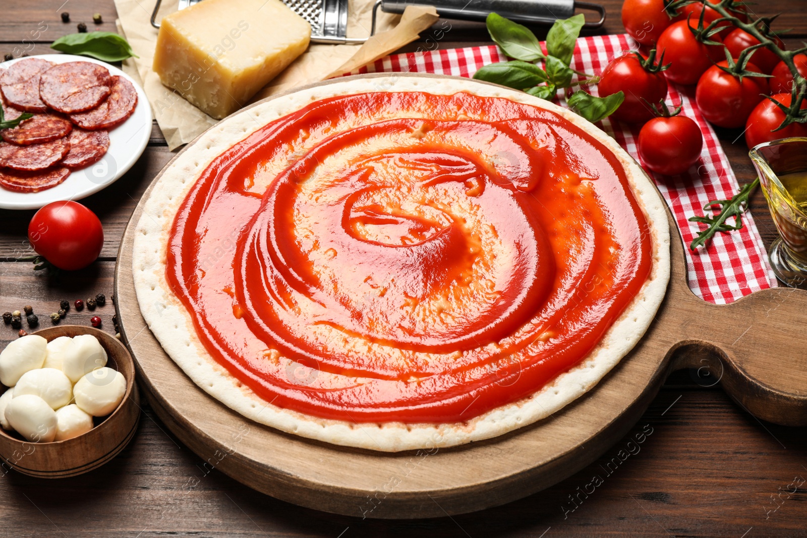 Photo of Base and fresh ingredients for pepperoni pizza on wooden table