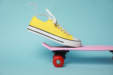 Yellow classic old school sneaker on skateboard against light blue background