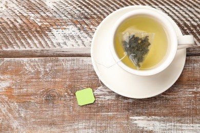 Tea bag in cup with hot drink on wooden rustic table, top view. Space for text