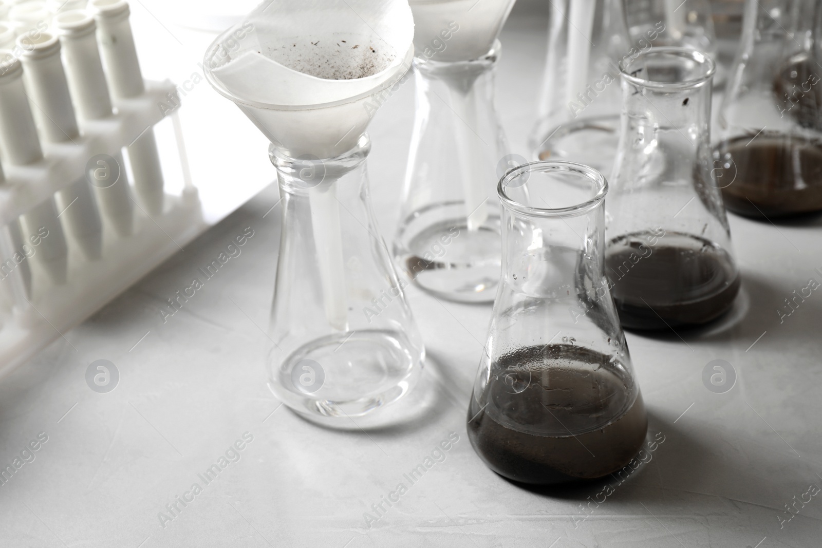 Photo of Laboratory glassware with soil extracts and funnels on table