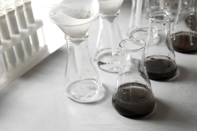 Laboratory glassware with soil extracts and funnels on table